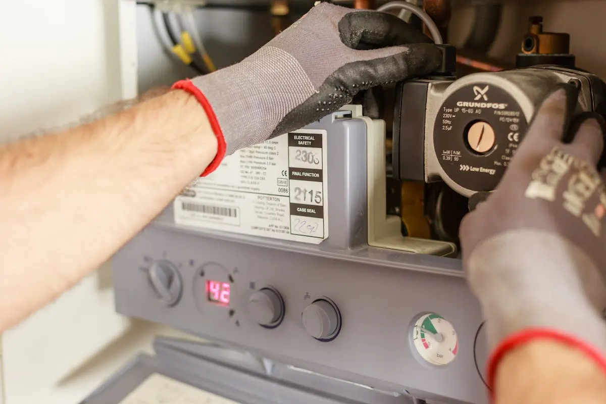 Plumber adjusting boiler pipes and instrumentation during a service call